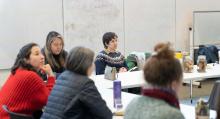 Group of people sitting at a table listening to a presenter 